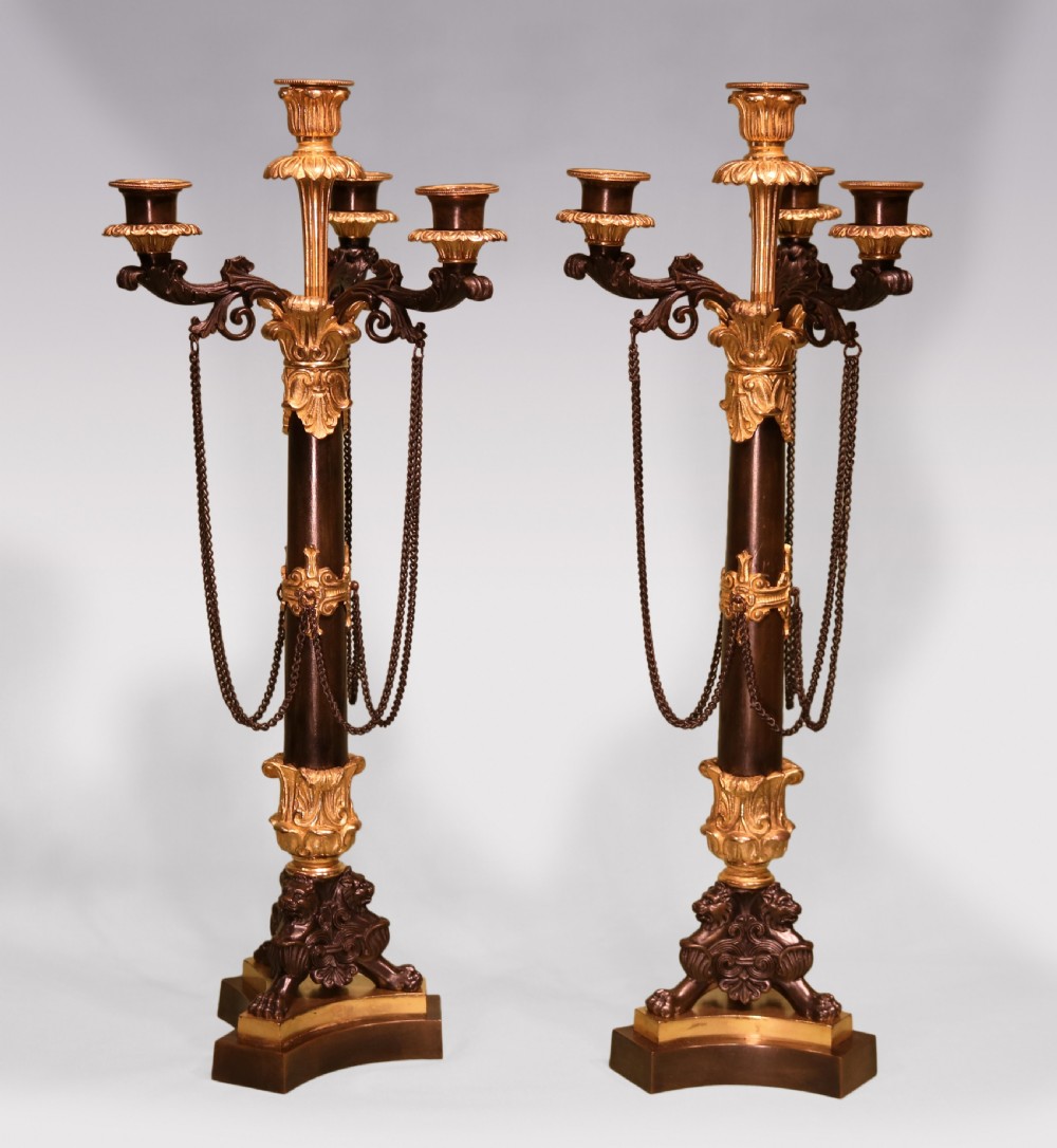 A pair of 19th-century French dark patinated bronze and gilt ormolu five-light candelabra with draped metal chains and scrolled bases.