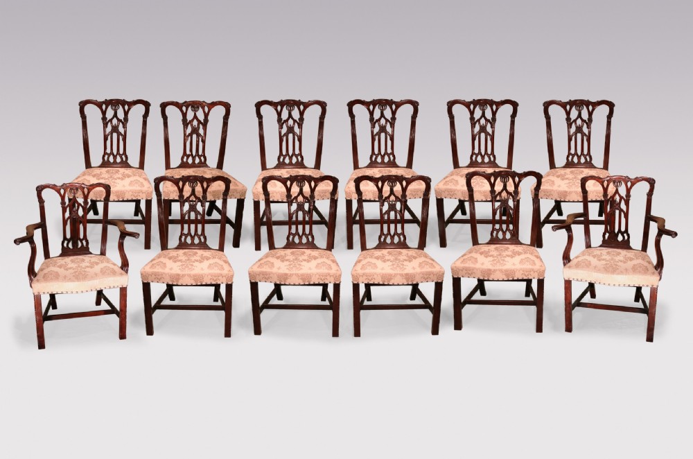 A set of twelve mid-nineteenth-century mahogany dining chairs with pierced Gothic tracery back splats and upholstered damask seats.