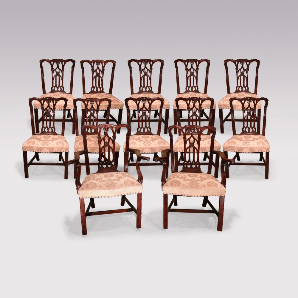 A set of twelve mid-nineteenth-century mahogany dining chairs with pierced Gothic tracery back splats and upholstered damask seats. View II