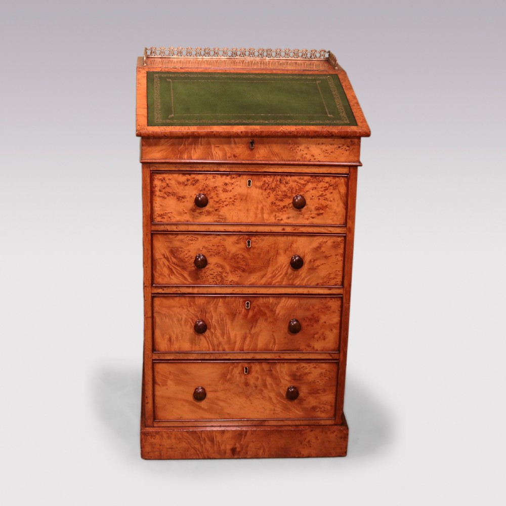 A mid 19th century burr elm Davenport desk featuring a green leather writing slope, brass gallery rail, and four stacked drawers.
