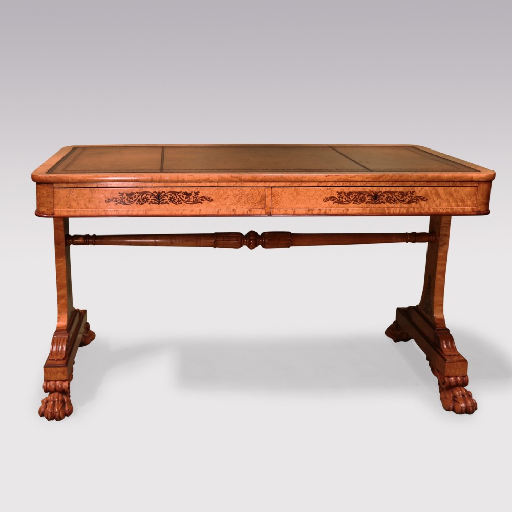 An early 19th-century birdseye maple writing table featuring a triple leather-tooled surface, inlaid floral aprons, and carved trestle legs. View II