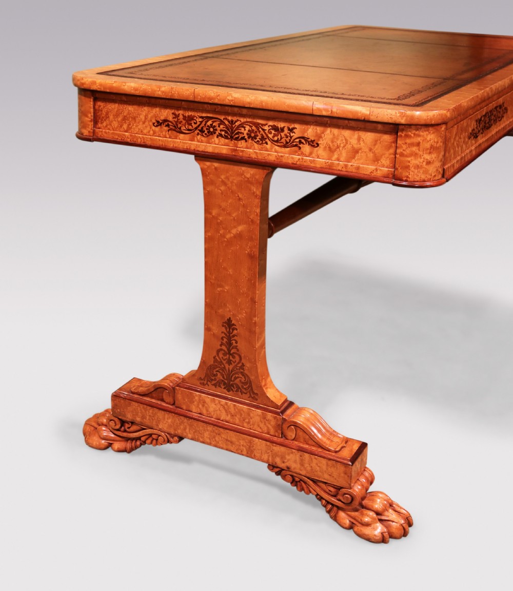 An early 19th-century birdseye maple writing table featuring a triple leather-tooled surface, inlaid floral aprons, and carved trestle legs. View IV