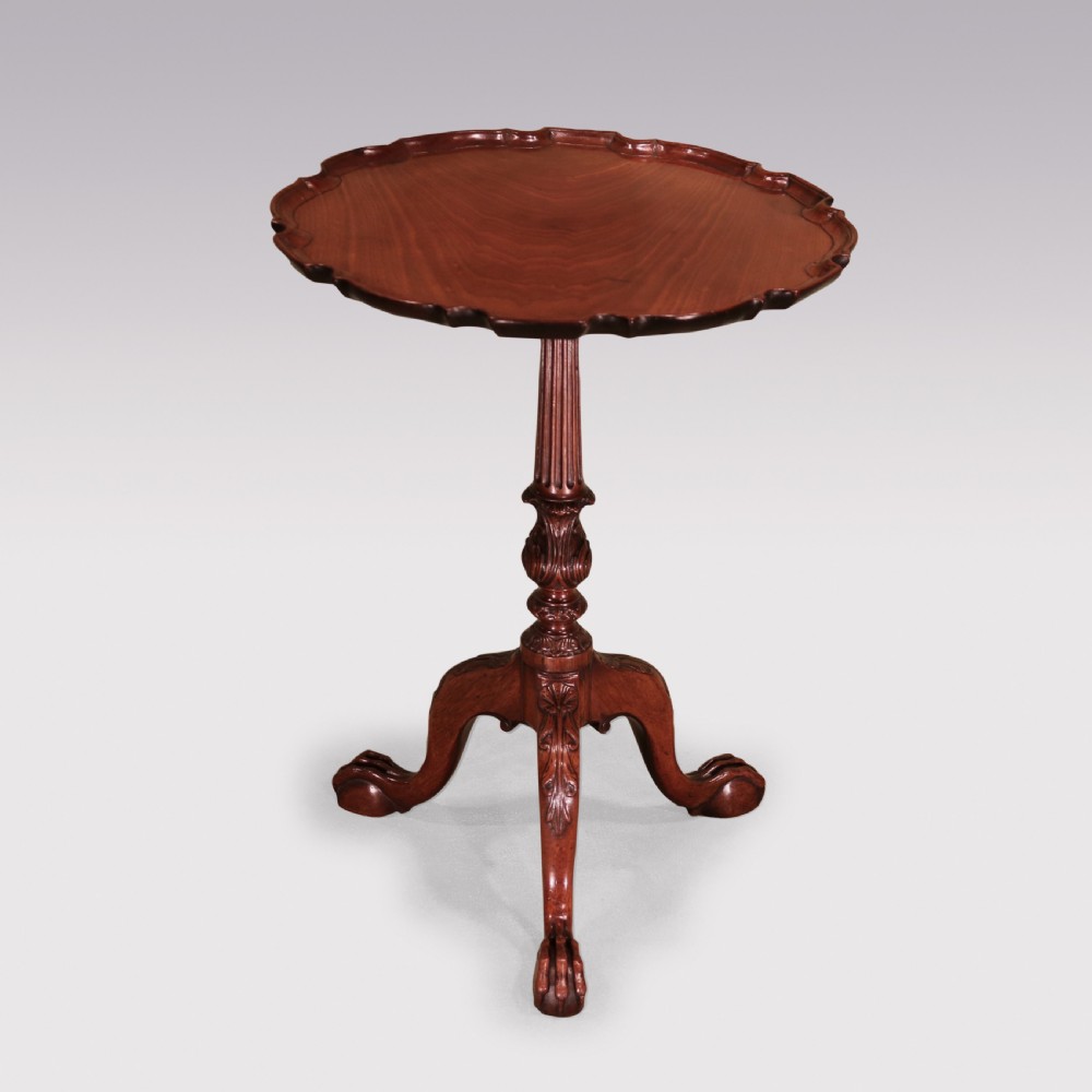 A George III mahogany tripod table featuring a scalloped piecrust top, fluted central pedestal, and cabriole legs with claw and ball feet.