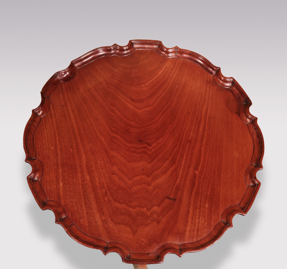 A George III mahogany tripod table featuring a scalloped piecrust top, fluted central pedestal, and cabriole legs with claw and ball feet. View II