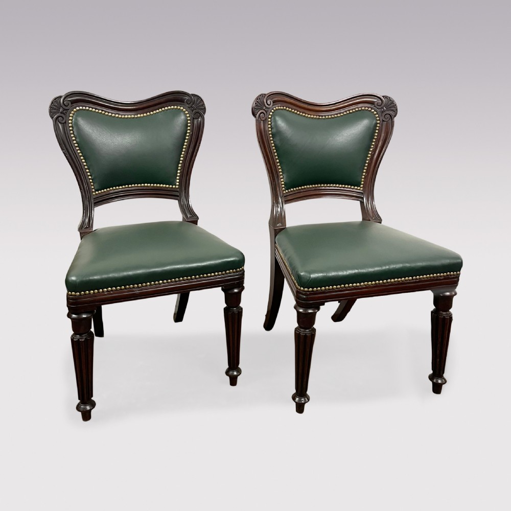 A set of ten Victorian mahogany dining chairs upholstered in forest green leather with brass stud trimming, featuring turned reeded legs and scrollwork carved backs, including two carver armchairs. View II