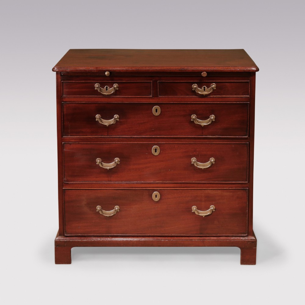 An antique George II mahogany chest of drawers with two short over three long drawers, brass swan-neck handles, bracket feet, and a pull-out brushing slide.