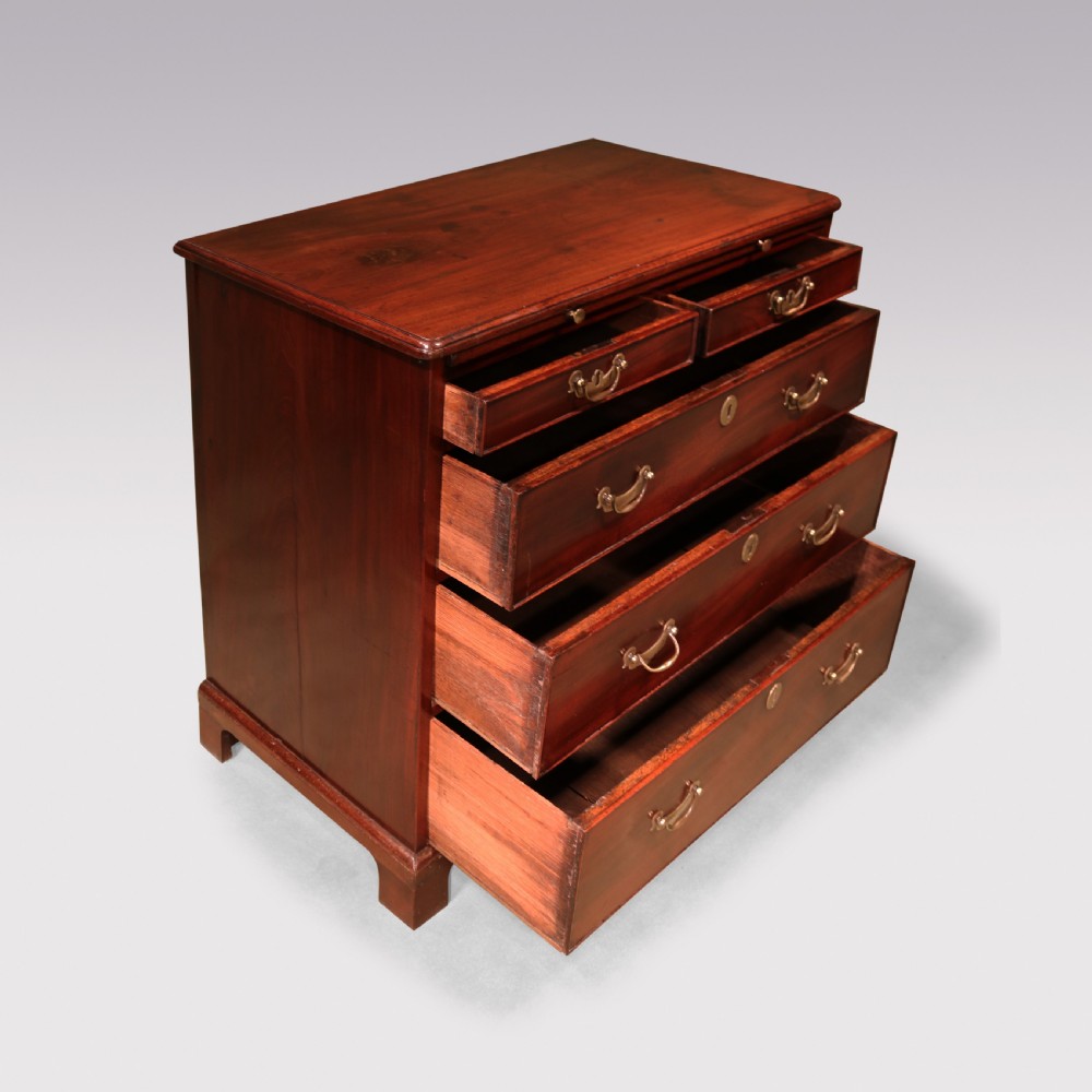 An antique George II mahogany chest of drawers with two short over three long drawers, brass swan-neck handles, bracket feet, and a pull-out brushing slide. View IV