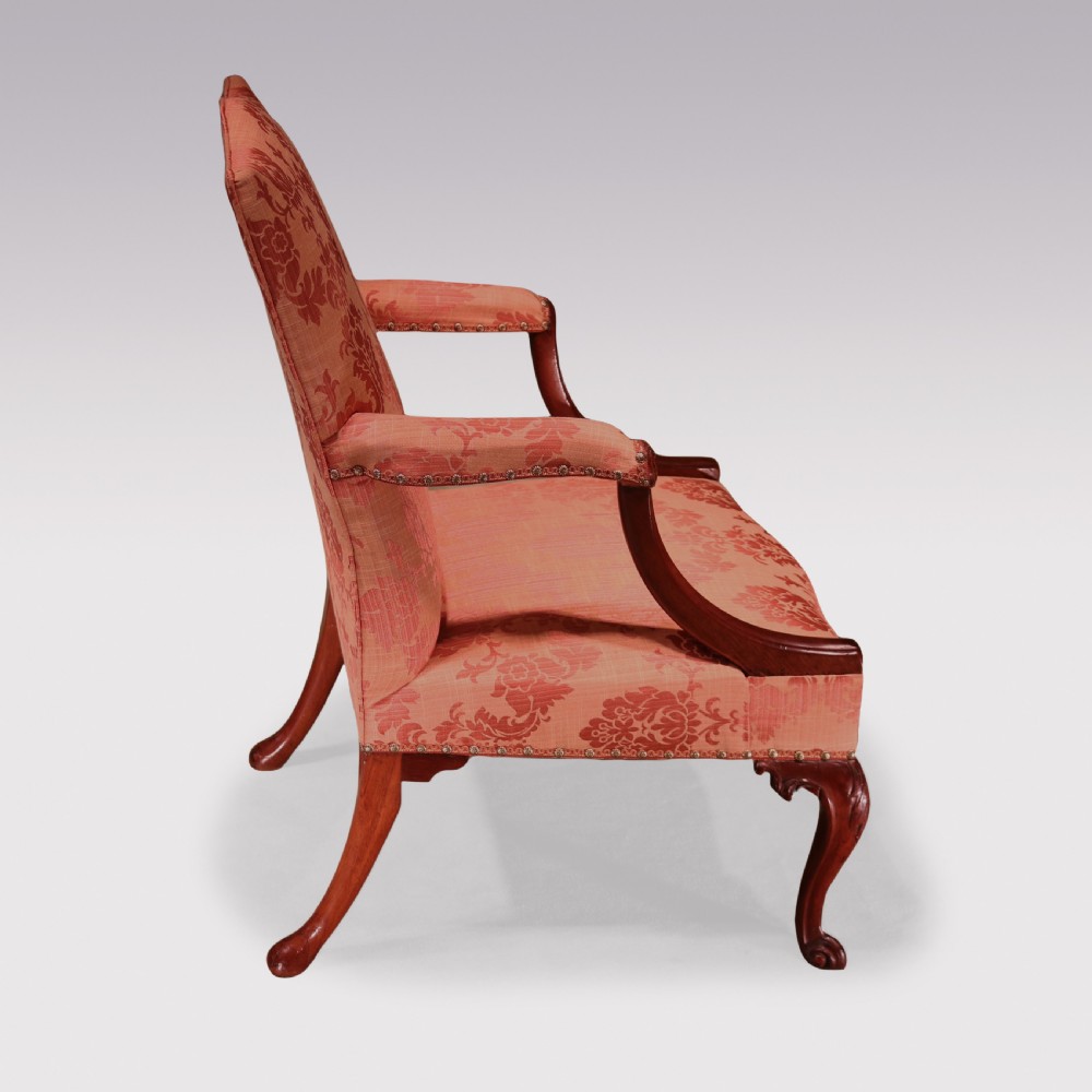 A George III mahogany Gainsborough library armchair upholstered in terracotta floral damask fabric with carved arm supports and cabriole legs. View III