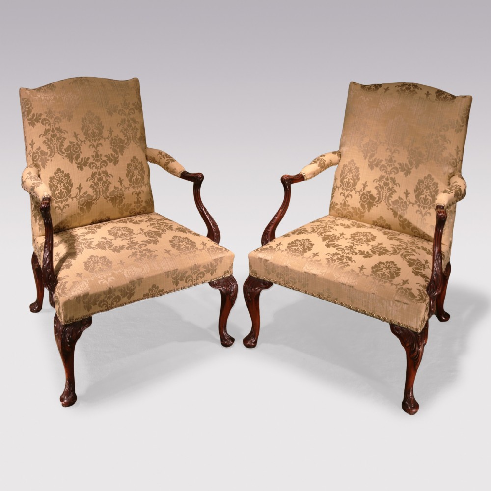 A pair of 19th-century Chippendale revival Gainsborough library armchairs upholstered in patterned gold damask fabric with carved mahogany frames and cabriole legs.