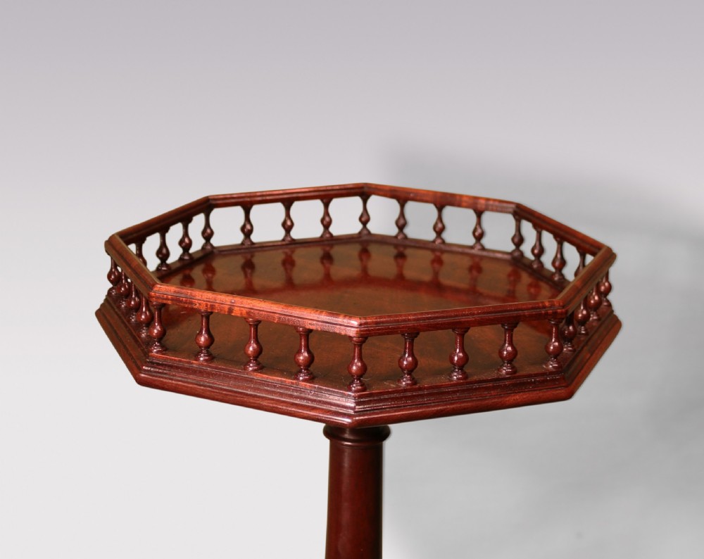 A George II mahogany kettle stand featuring an octagonal spindle-gallereed top supported on a turned central column and tripod cabriole legs. View II