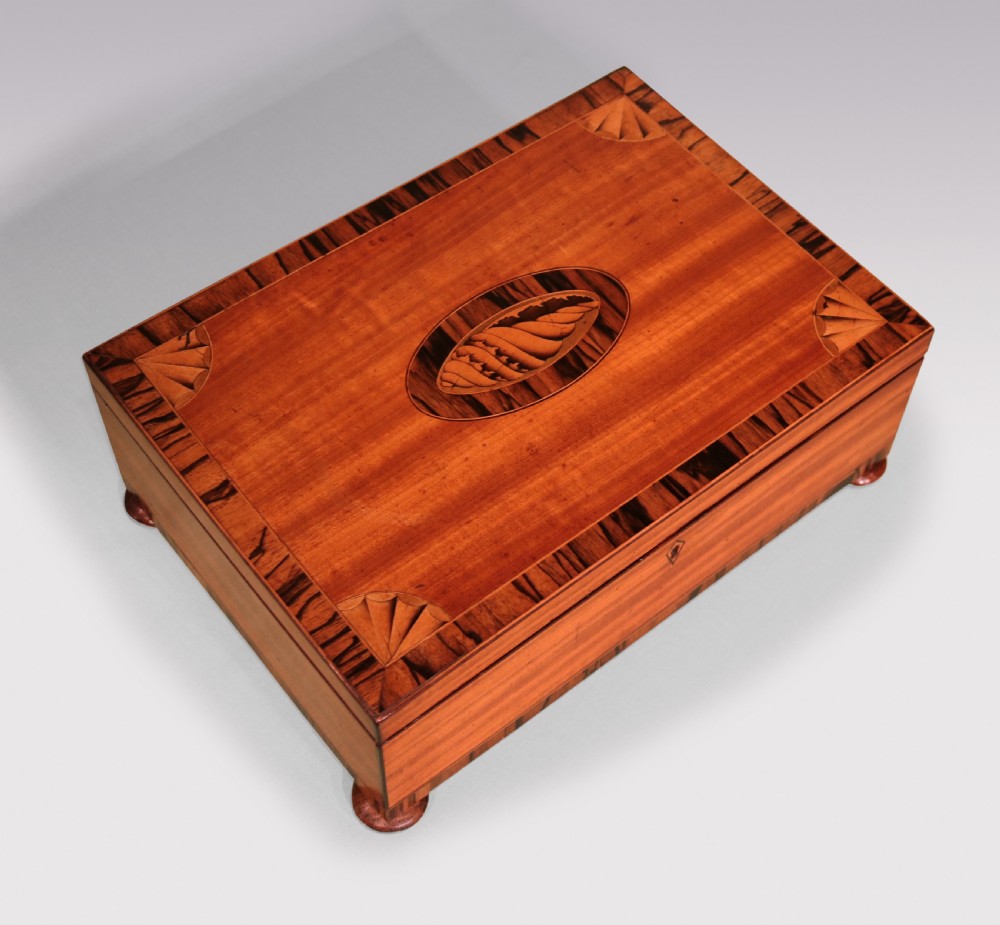 A rectangular George III satinwood box featuring a central oval shell marquetry inlay, fan corner motifs, and striped calamander crossbanding.