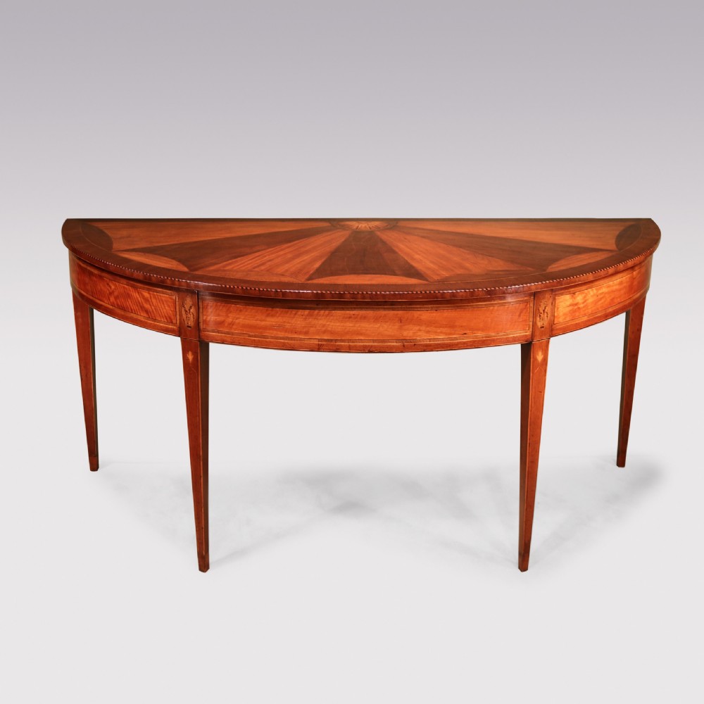A semi-circular George III satinwood and padoukwood console table featuring a sunburst inlaid top and square tapered legs.