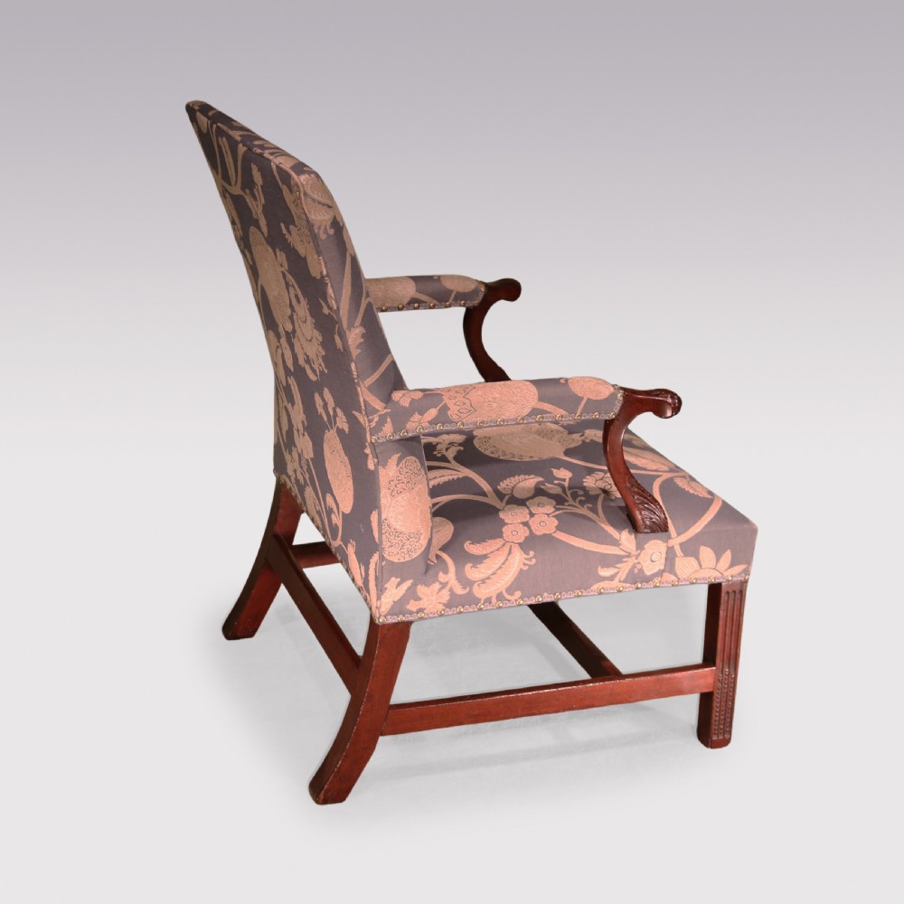 A George III mahogany armchair featuring floral patterned damask upholstery, brass stud detailing, curved carved arms, and fluted square front legs. View II