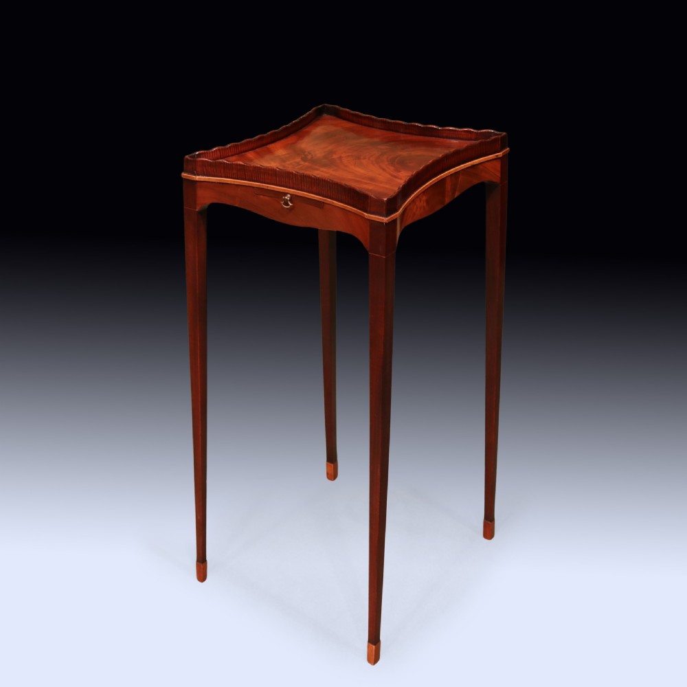 A late 18th-century Sheraton mahogany kettle stand featuring a scalloped gallery top, pull-out slide, and slender square tapered legs. View II