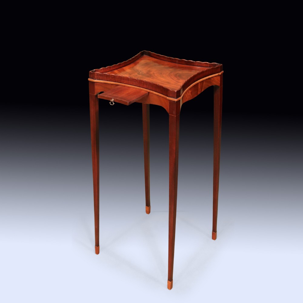A late 18th-century Sheraton mahogany kettle stand featuring a scalloped gallery top, pull-out slide, and slender square tapered legs. View III