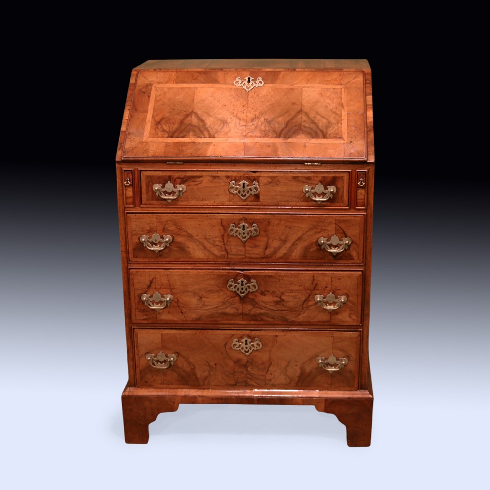 An eighteenth-century George II walnut bureau featuring a sloping fall-front lid over four graduated drawers with engraved brass handles and bracket feet. View II