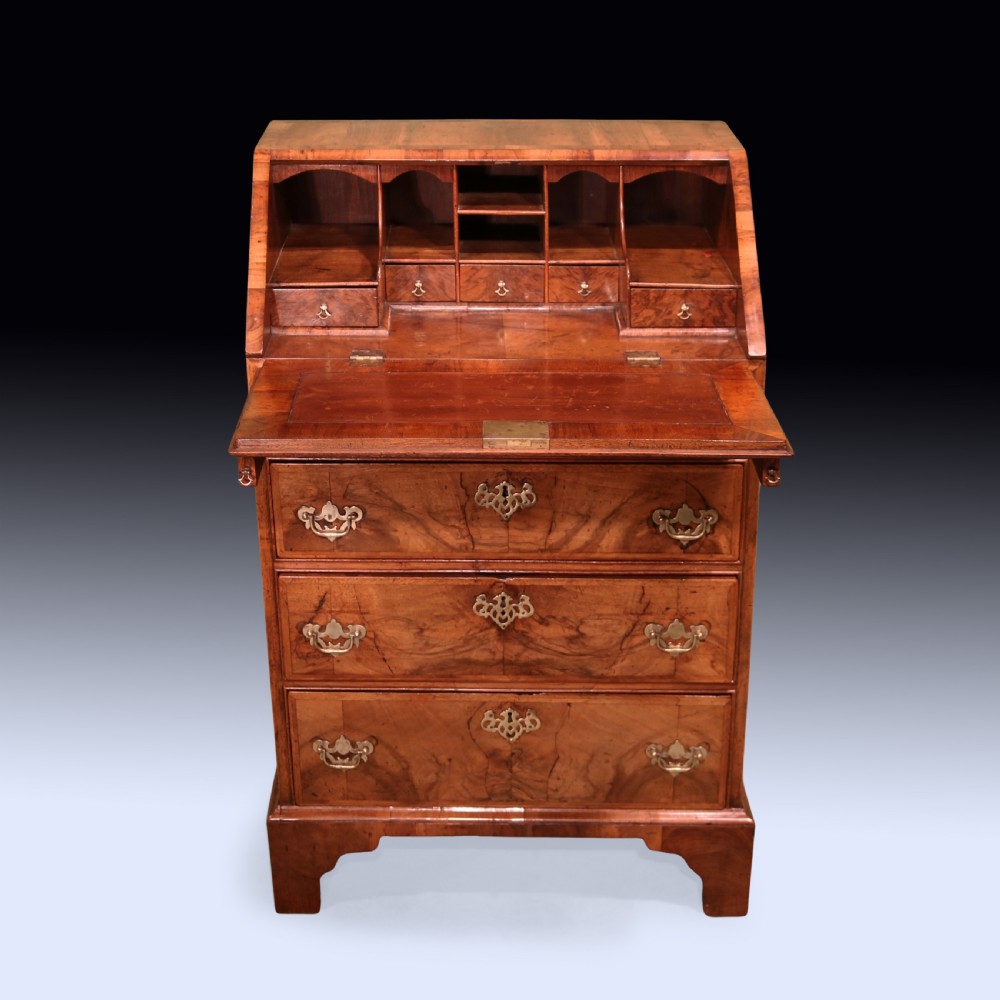 An eighteenth-century George II walnut bureau featuring a sloping fall-front lid over four graduated drawers with engraved brass handles and bracket feet. View III