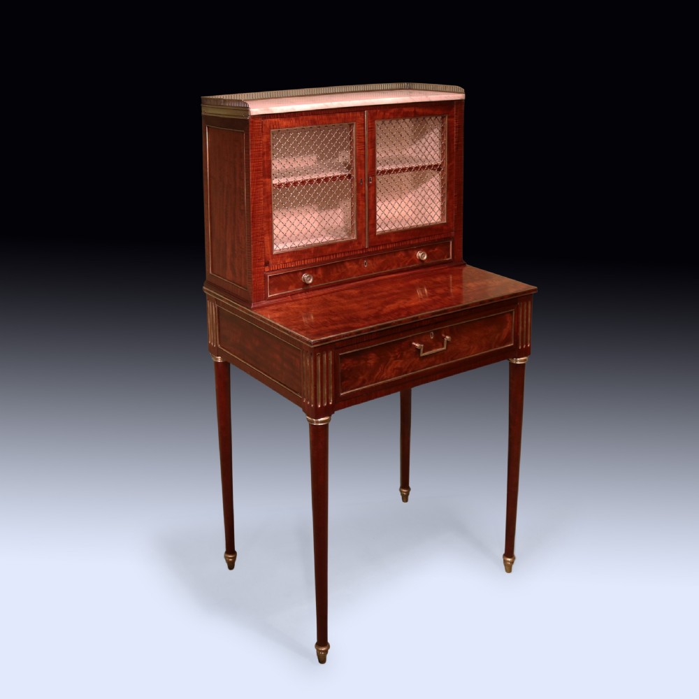 A pair of Regency period mahogany bonheur du jours featuring brass wire grille cabinet doors, marble tops, and slender turned legs. View II