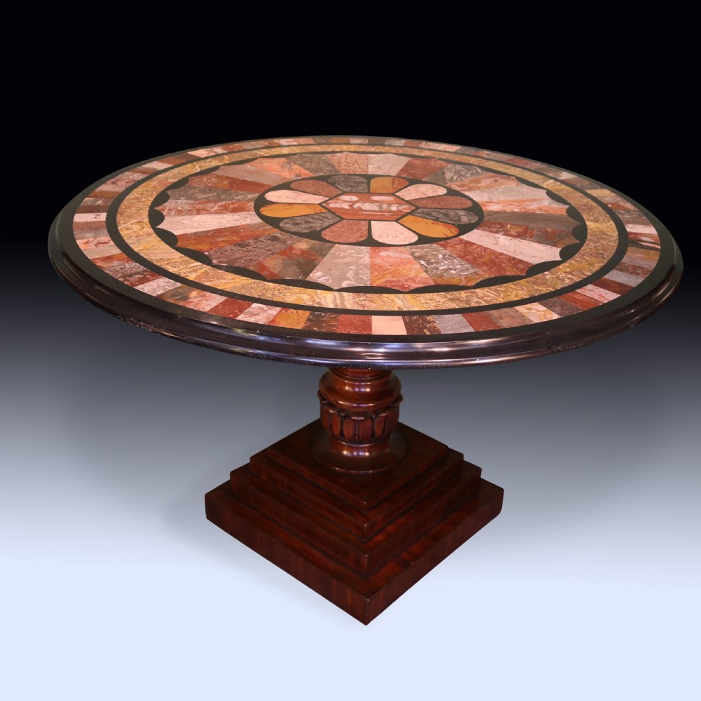A 19th-century round centre table with an inlaid geometric specimen marble top supported by a carved mahogany pedestal base.