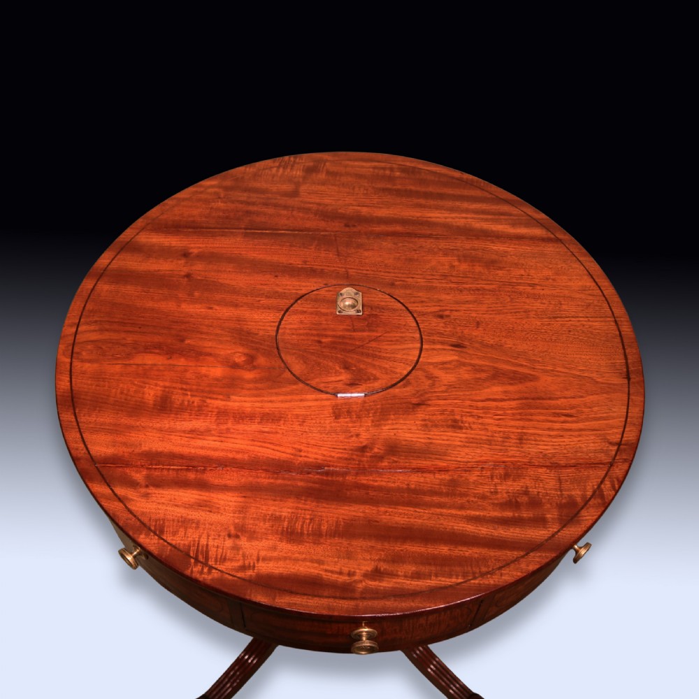 An early 19th-century circular mahogany drum table with perimeter drawers, a reeded central pedestal, and four splayed legs with brass castors. View II