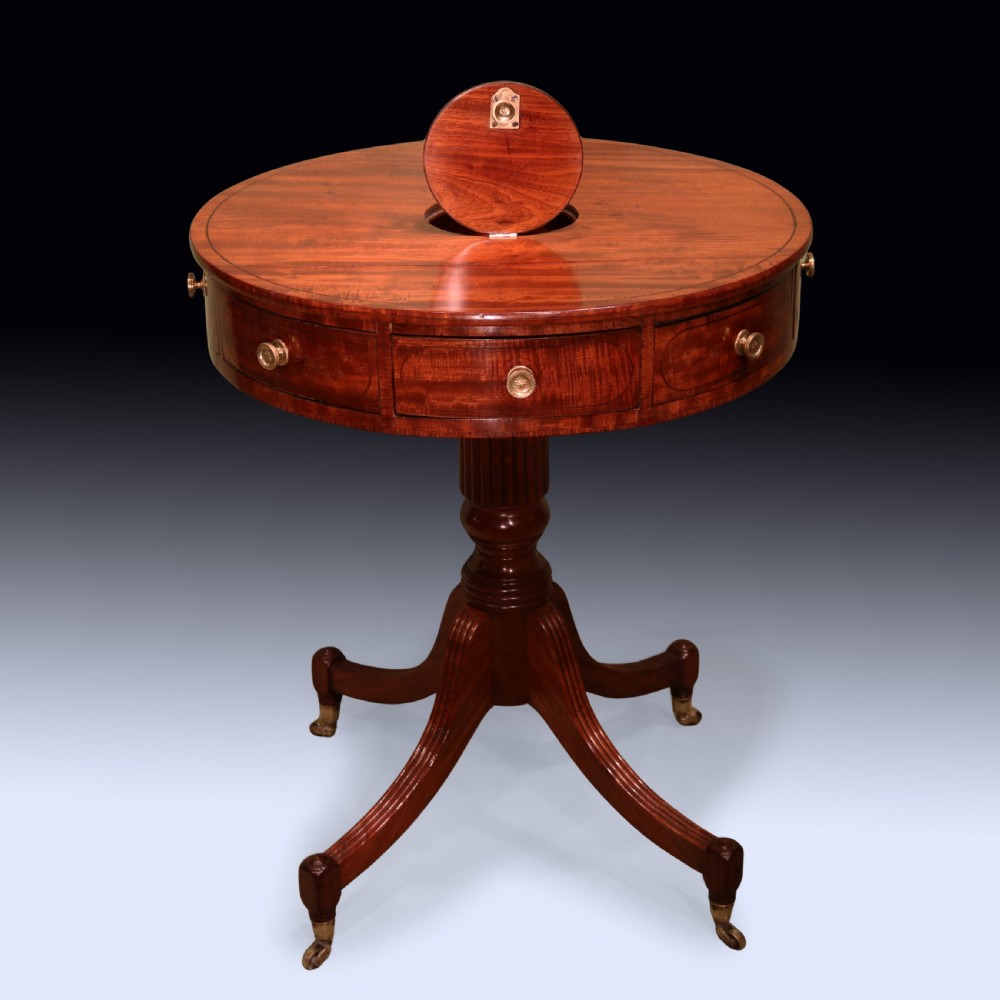 An early 19th-century circular mahogany drum table with perimeter drawers, a reeded central pedestal, and four splayed legs with brass castors. View III