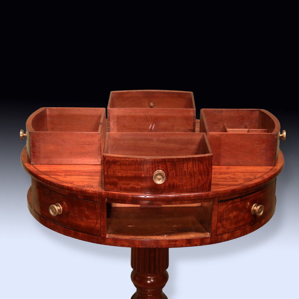 An early 19th-century circular mahogany drum table with perimeter drawers, a reeded central pedestal, and four splayed legs with brass castors. View IV