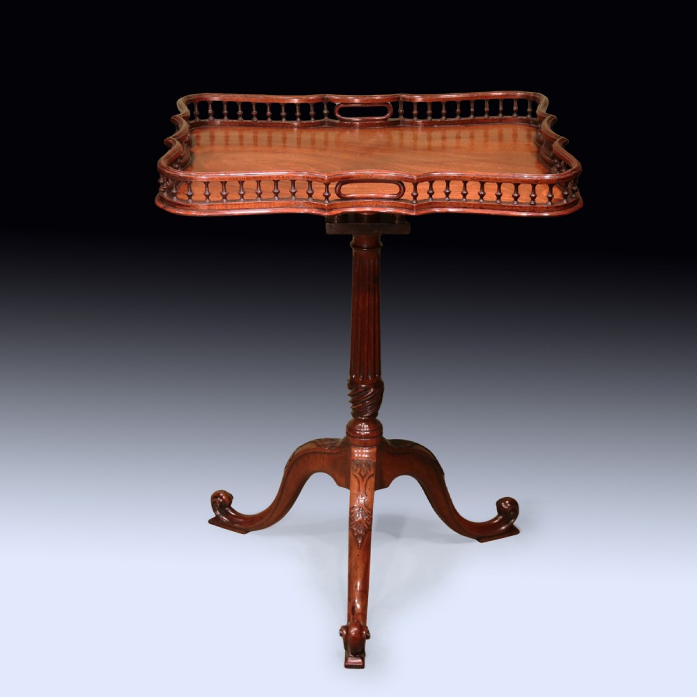 An antique Chippendale style mahogany tripod wine table featuring a rectangular tray top with a spindle gallery and turned pedestal base.