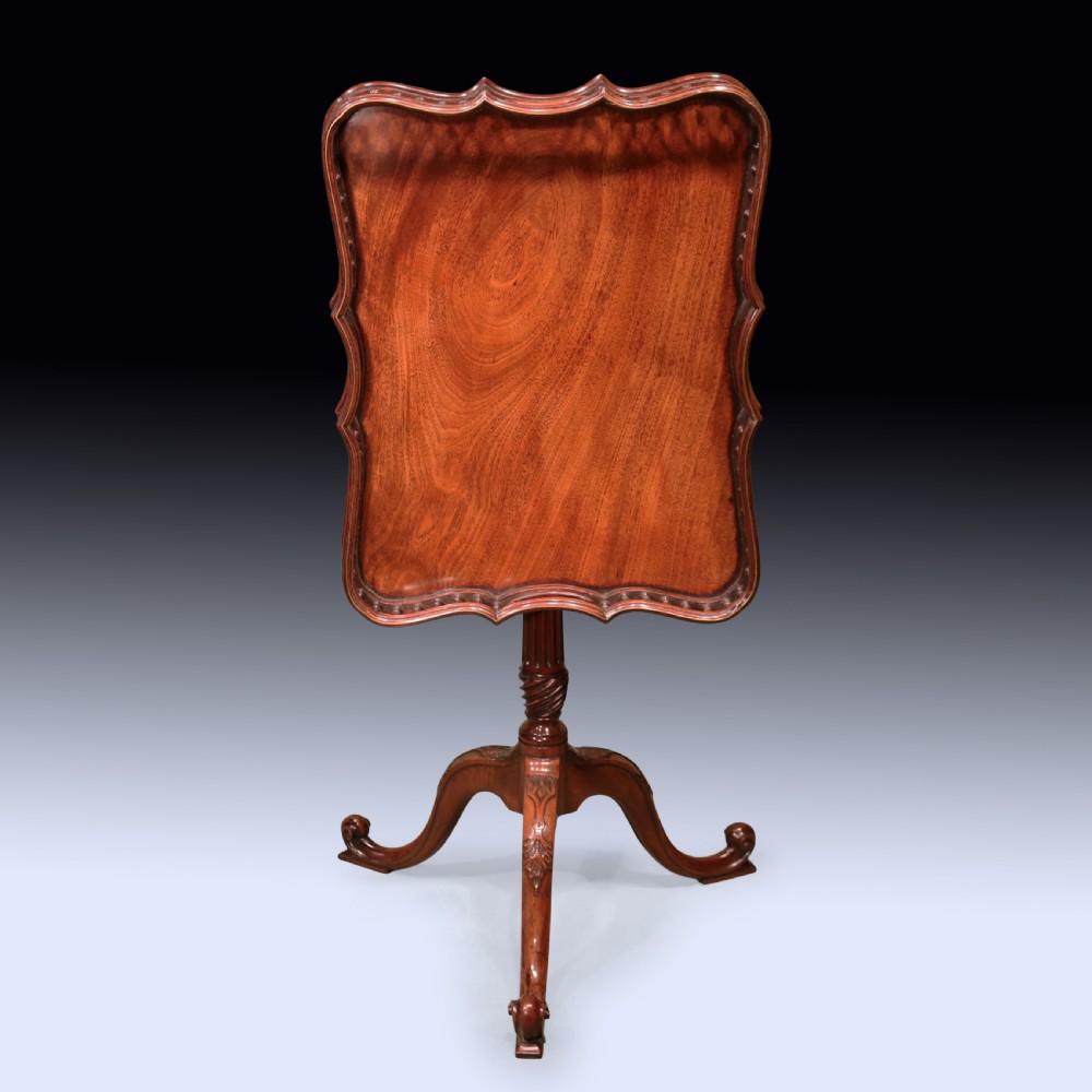An antique Chippendale style mahogany tripod wine table featuring a rectangular tray top with a spindle gallery and turned pedestal base. View II
