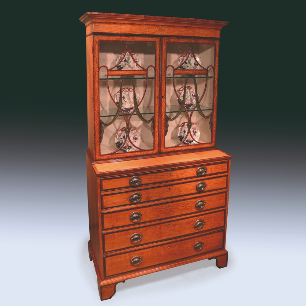 A Sheraton period satinwood secretaire bookcase featuring astagal glazed doors on the upper display cabinet over a chest of drawers.