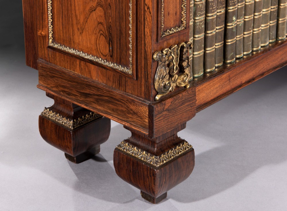 A matching pair of 19th-century Regency dark rosewood open bookcases featuring upper brass tiered shelves and corner mounts. View V