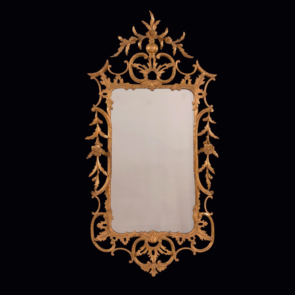 An antique Chippendale period giltwood wall mirror featuring carved openwork rococo frame with C-scrolls and acanthus leaves enclosing a rectangular plate.