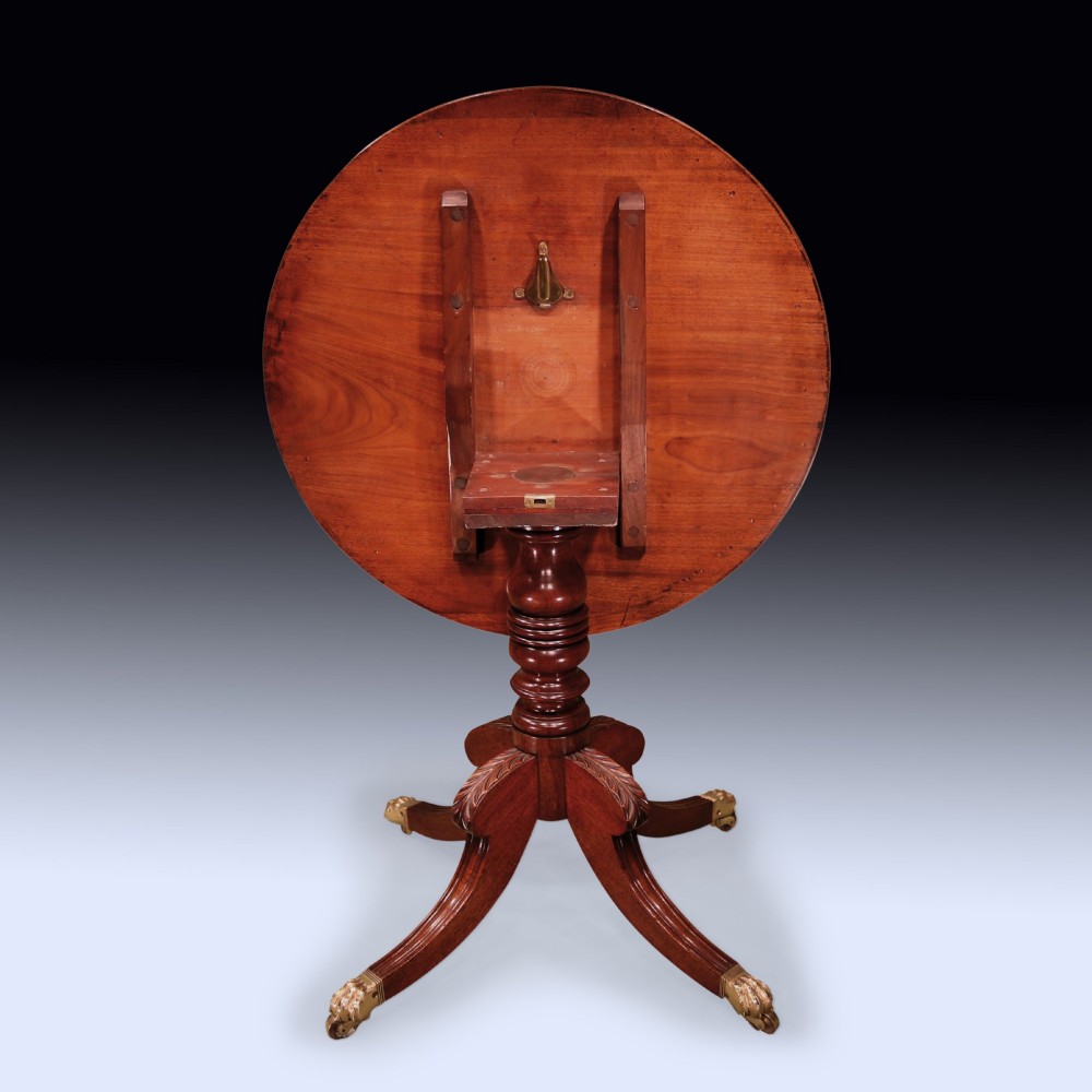 A circular mahogany occasional table featuring a crossbanded top, turned central pedestal, and four splayed legs with brass lion paw feet. View III
