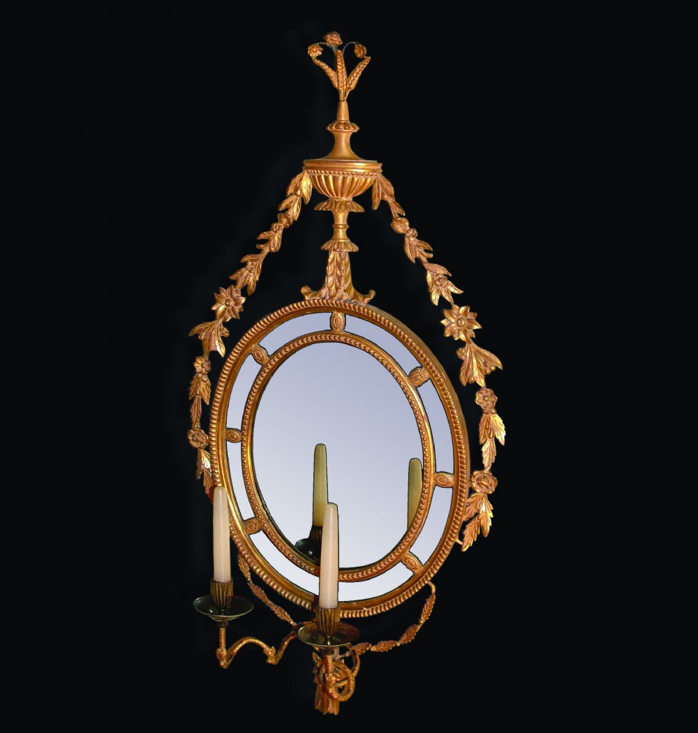 A pair of late 18th-century Neoclassical oval giltwood girandole mirrors with floral swags, urn finials, and twin candle branches. View IV