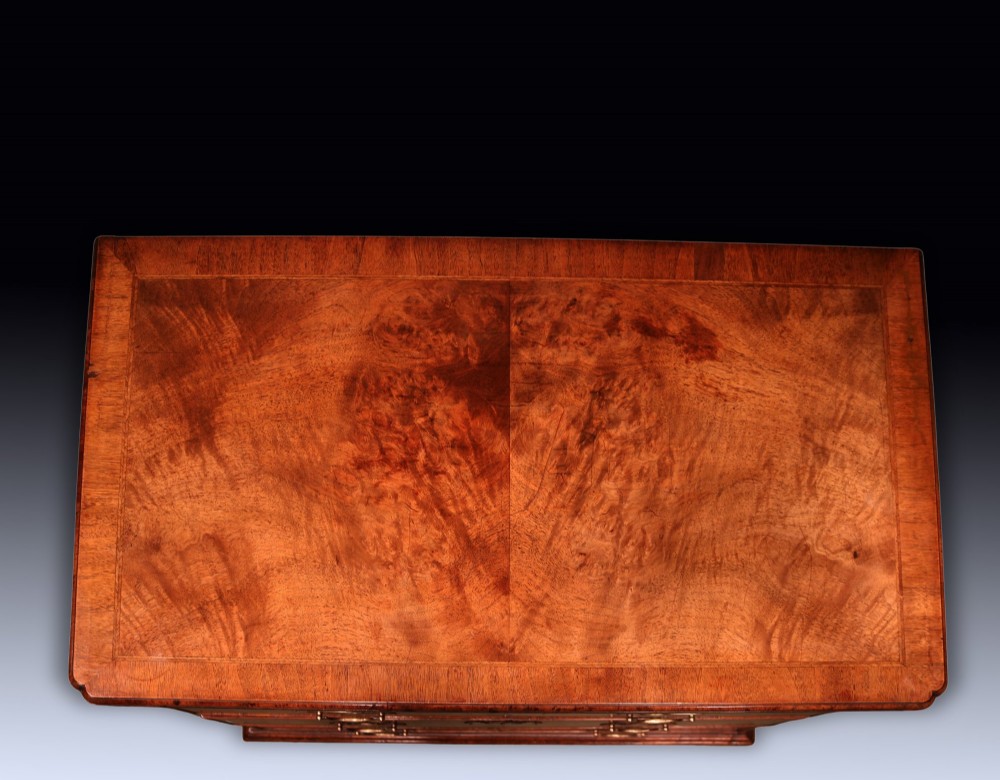 A George II period walnut chest of drawers featuring two short drawers over three long graduated drawers with brass handles and bracket feet. View III