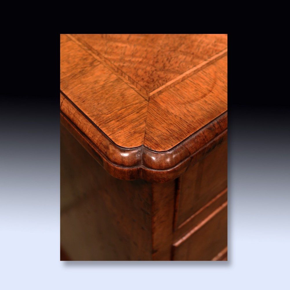 A George II period walnut chest of drawers featuring two short drawers over three long graduated drawers with brass handles and bracket feet. View IV