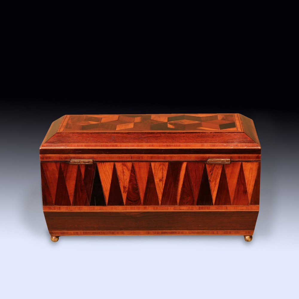 A Regency period wooden tea caddy featuring geometric parquetry inlay, a hinged lid, and small brass feet. View III
