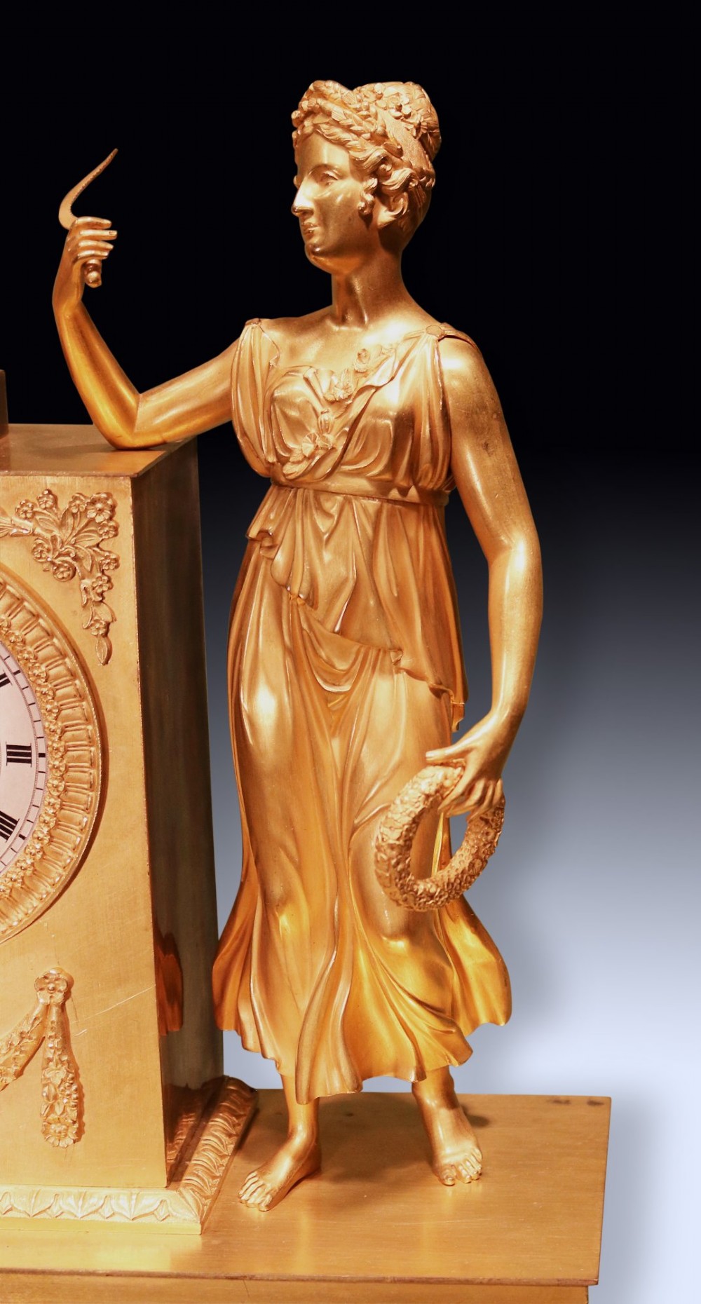 An early 19th-century French gilt bronze ormolu clock featuring a classical female figure standing beside a rectangular housing topped with a fruit basket. View III