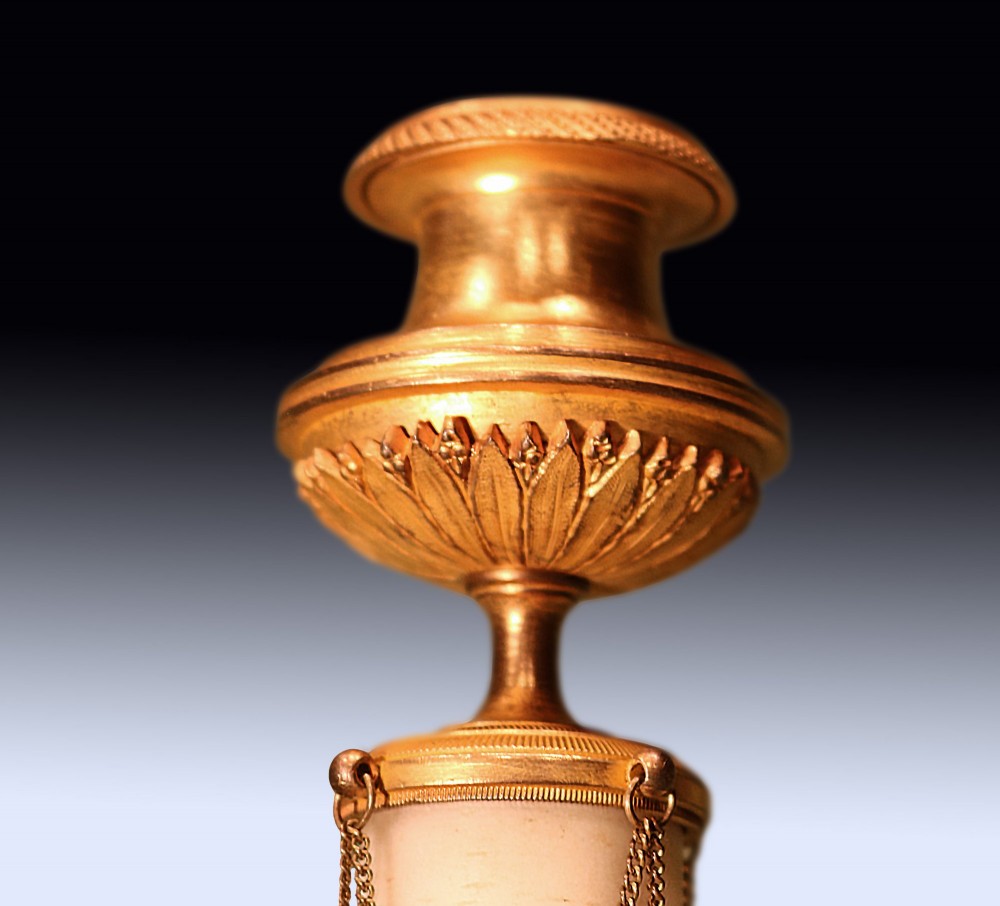 A pair of 19th-century Neoclassical candlesticks featuring white marble cylindrical columns adorned with gilt bronze chain swags and urn-shaped sconces resting on circular bases. View III