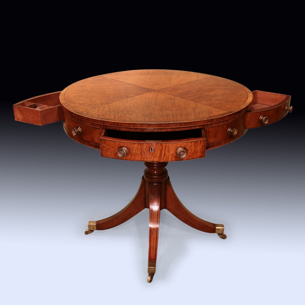 A George III mahogany drum table featuring a circular top with drawers around the apron, supported by a turned pedestal column and four splayed legs with brass castors. View II