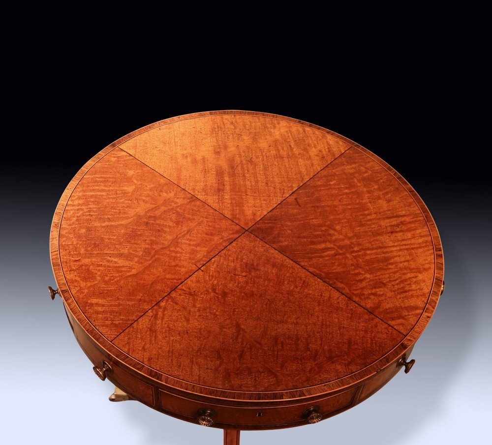 A George III mahogany drum table featuring a circular top with drawers around the apron, supported by a turned pedestal column and four splayed legs with brass castors. View IV
