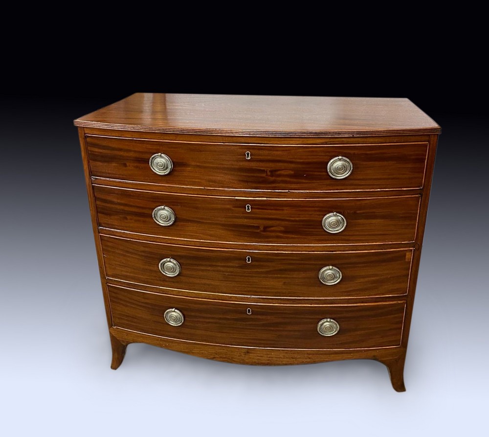 A George III mahogany chest of drawers featuring a curved bow front, four graduated drawers with circular brass ring handles, and short splayed feet.