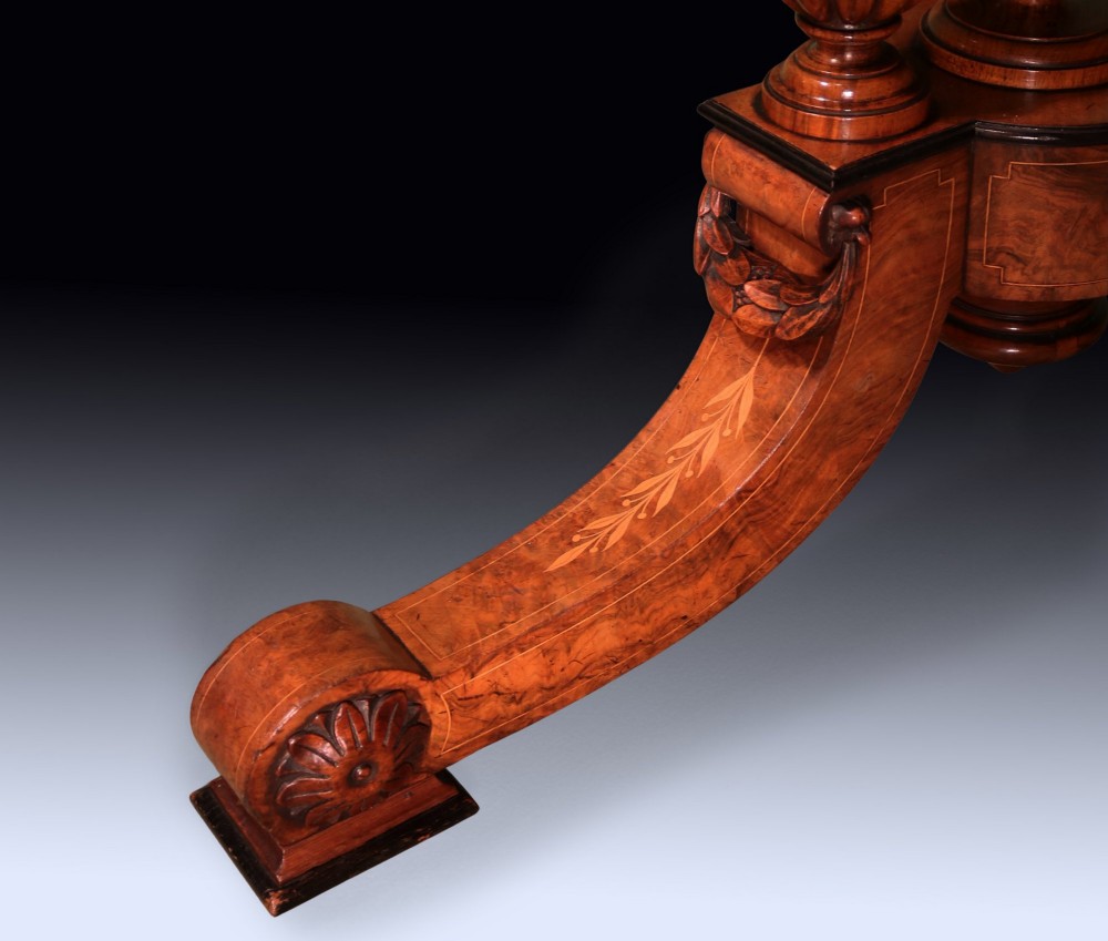 A circular mid 19th-century burr walnut centre table featuring central marquetry inlay and a carved pedestal base with splayed legs. View VI