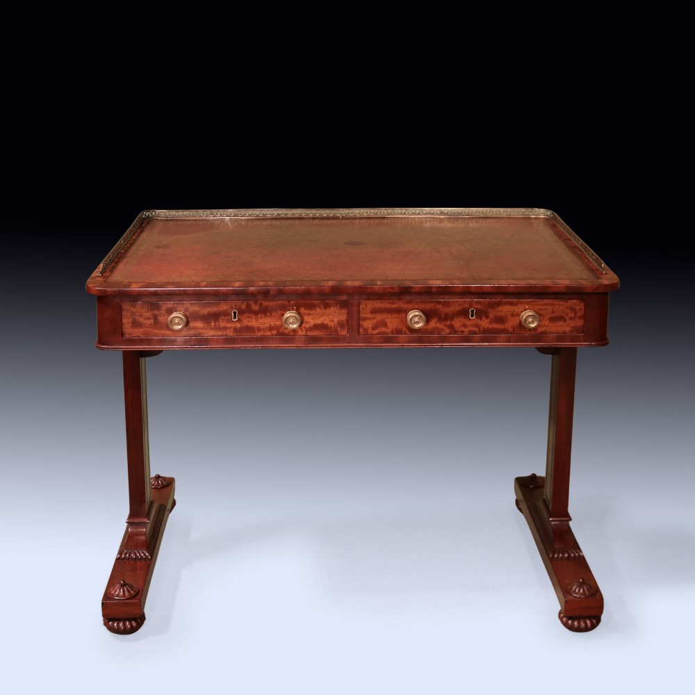 An antique Regency period mahogany writing table featuring an inset leather top, a brass gallery rail, and drawers set on twin end supports. View II