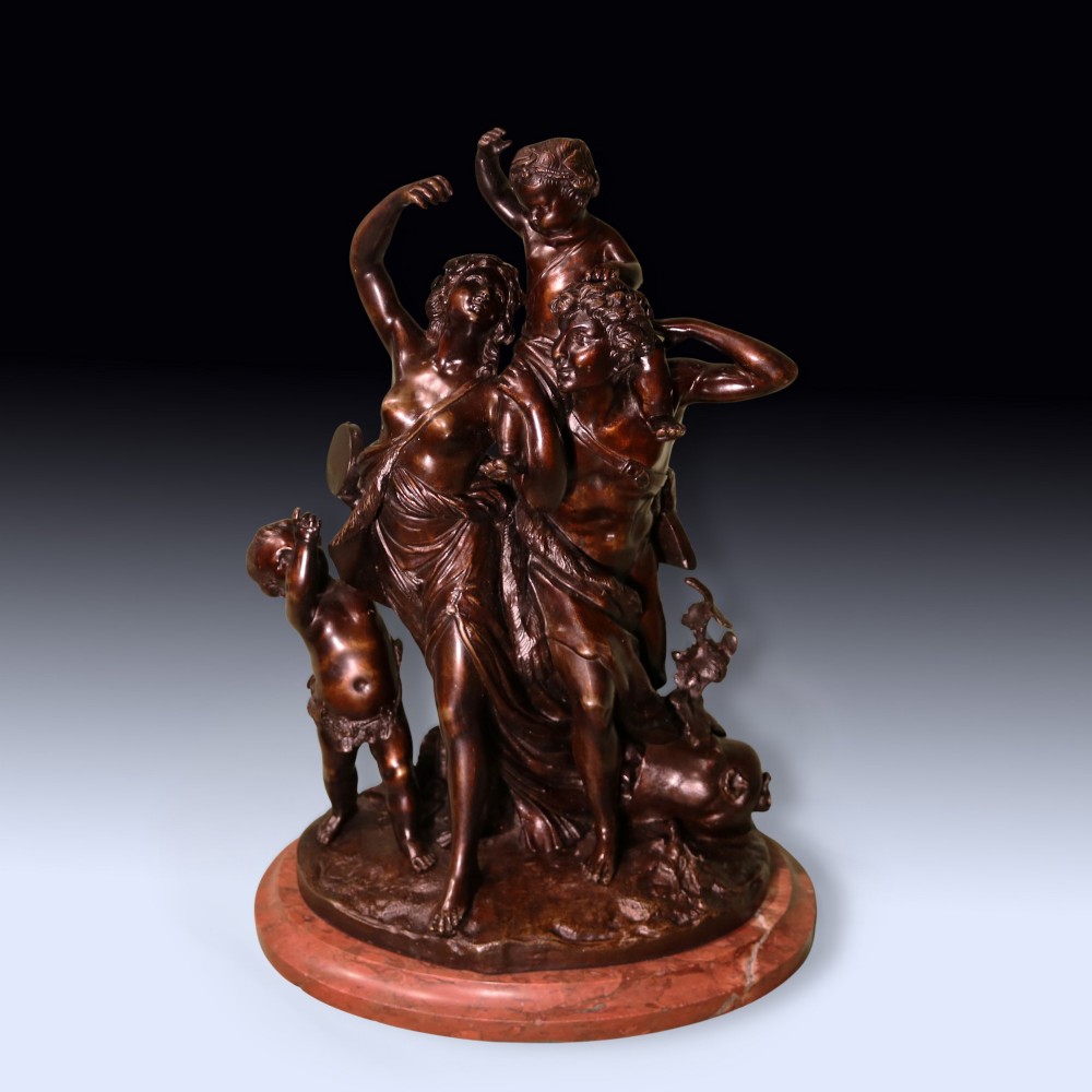 A 19th-century patinated bronze sculpture depicting Bacchanalian classical figures and cherubs mounted on a circular red marble base.