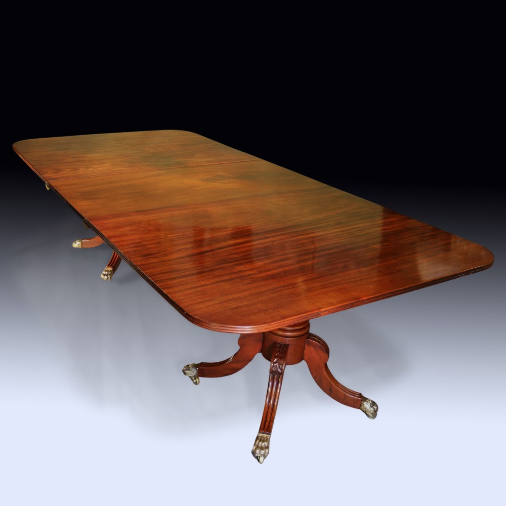 An early 19th-century mahogany twin pedestal dining table featuring rounded ends, turned central columns, reeded splayed legs, and brass claw castors. View III
