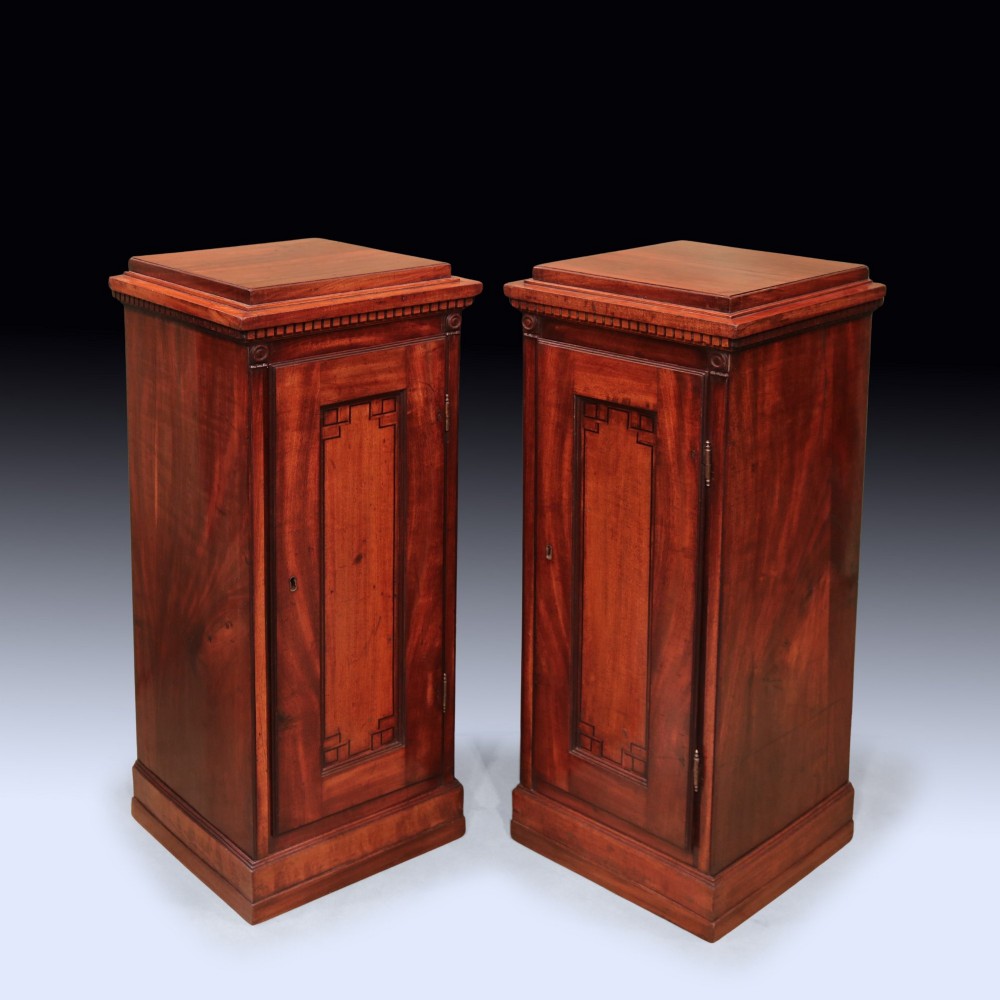 A pair of matching George III period mahogany pedestal cupboards featuring flame mahogany panel doors and plinth bases.