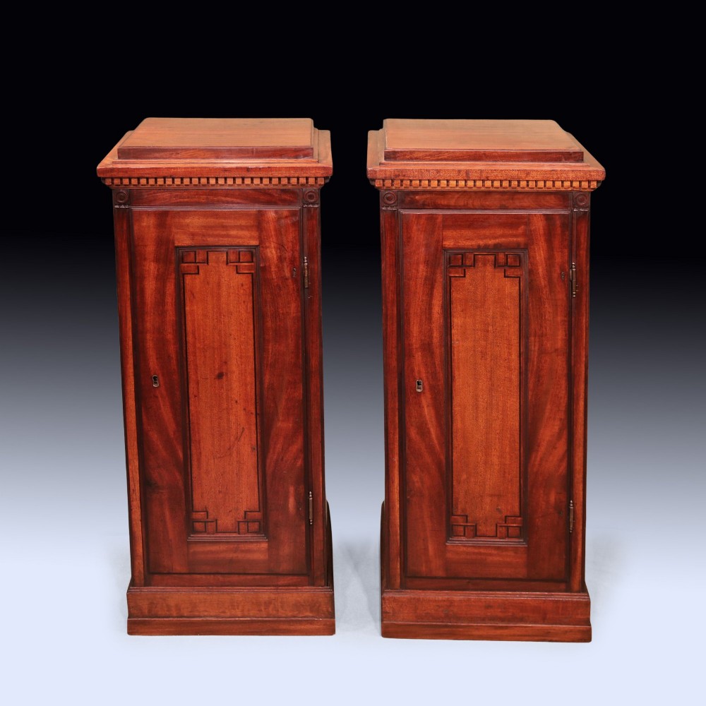 A pair of matching George III period mahogany pedestal cupboards featuring flame mahogany panel doors and plinth bases. View II