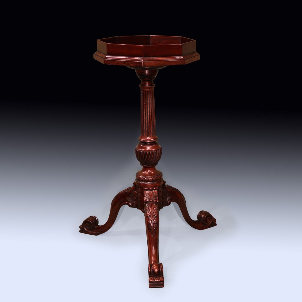 A dark mahogany tripod kettle stand featuring an octagonal tray top, fluted column stem, and carved acanthus leaf cabriole legs with scroll feet.