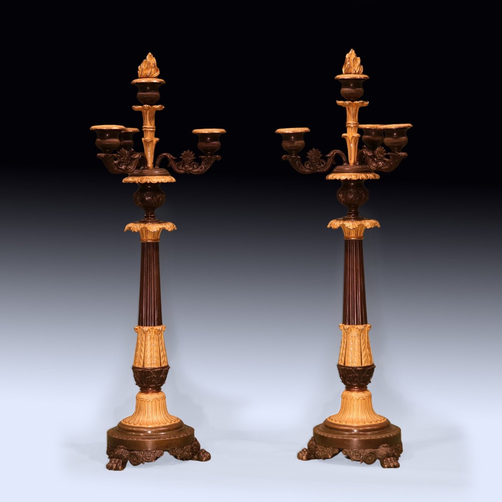 A pair of tall Regency period bronze and ormolu four-light candelabra featuring fluted shafts, gilt leaf detailing, and paw feet.