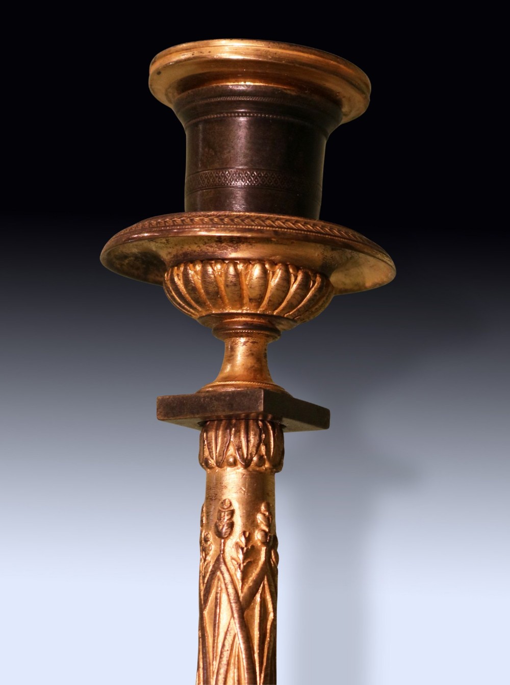 A pair of 19th-century French Empire style candlesticks featuring patinated bronze columns supported by gilded ormolu winged lions on square bases. View IV